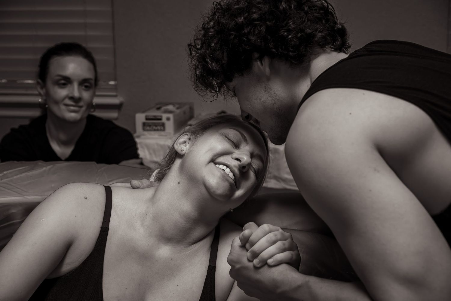 A candid black and white photo captures people sharing a joyful moment of laughter and connection around a table.