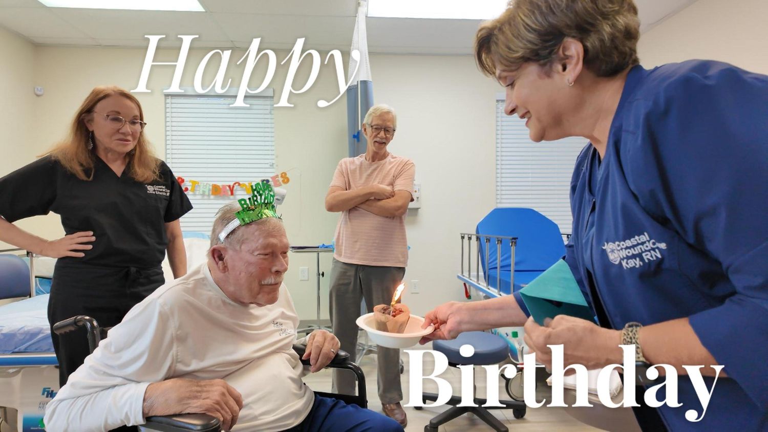 Someone wearing a festive green "Happy Birthday" crown and a white t-shirt with palm trees in what appears to be an office setting.