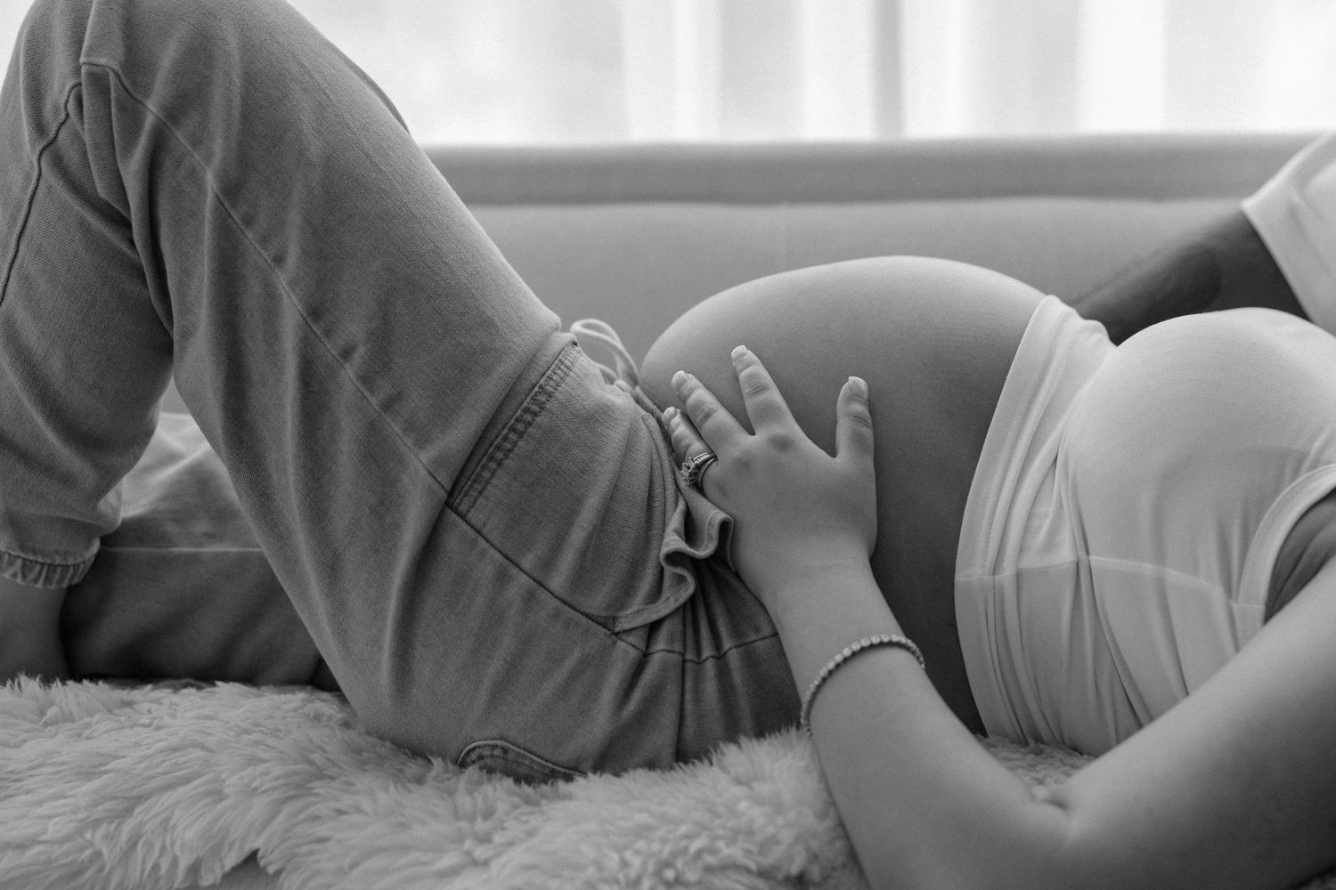 Black and white maternity photo series showing intimate moments of a pregnant woman's belly during pregnancy.
