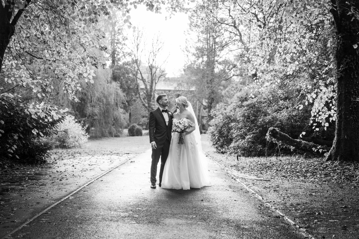 A glowing autumn wedding scene shows a bride in a white lace dress holding a pastel bouquet among fallen leaves.
