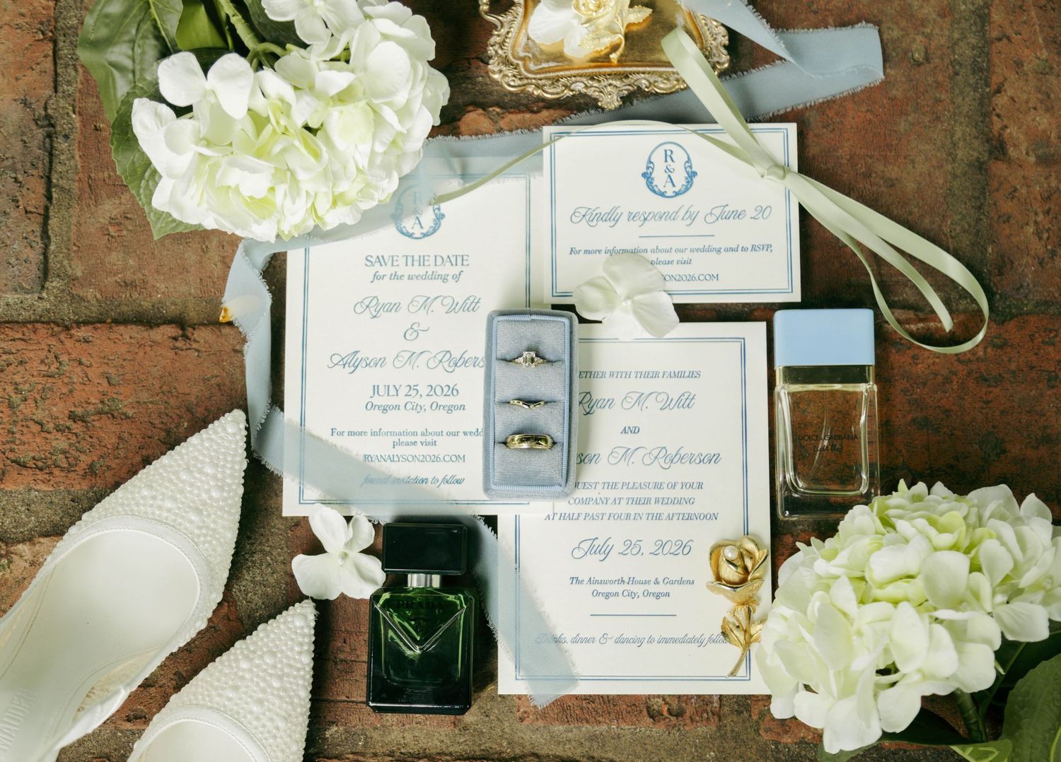 A small wooden ring box sits beside pink and white flowers on a vintage-style blue patterned background.