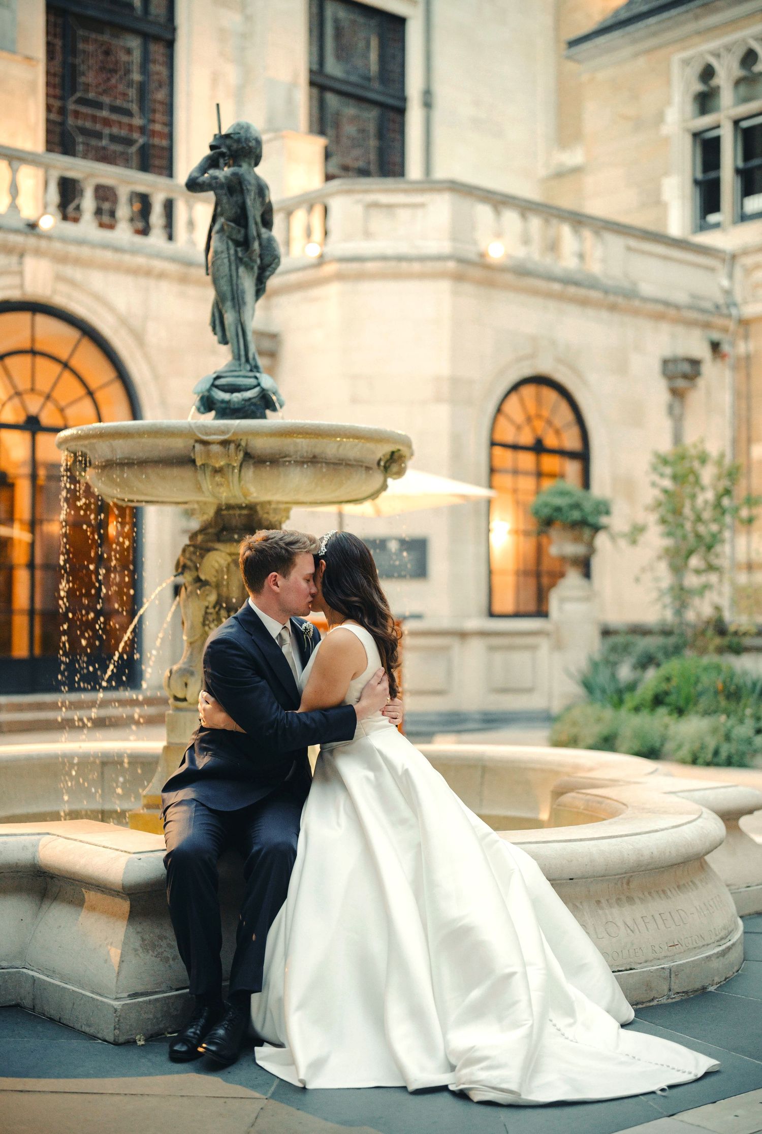 Romantic wedding portraits by an elegant fountain at dusk.