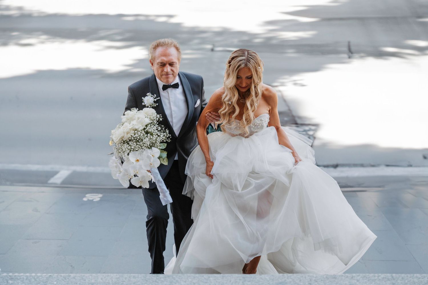 Newlywed couple dancing together on a concrete floor with the bride's white dress flowing elegantly in motion.