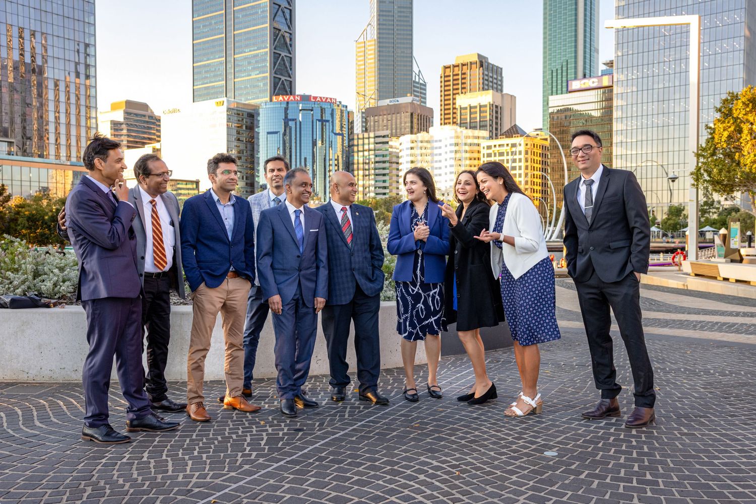 Business professionals stand together in front of modern glass buildings in an urban setting.