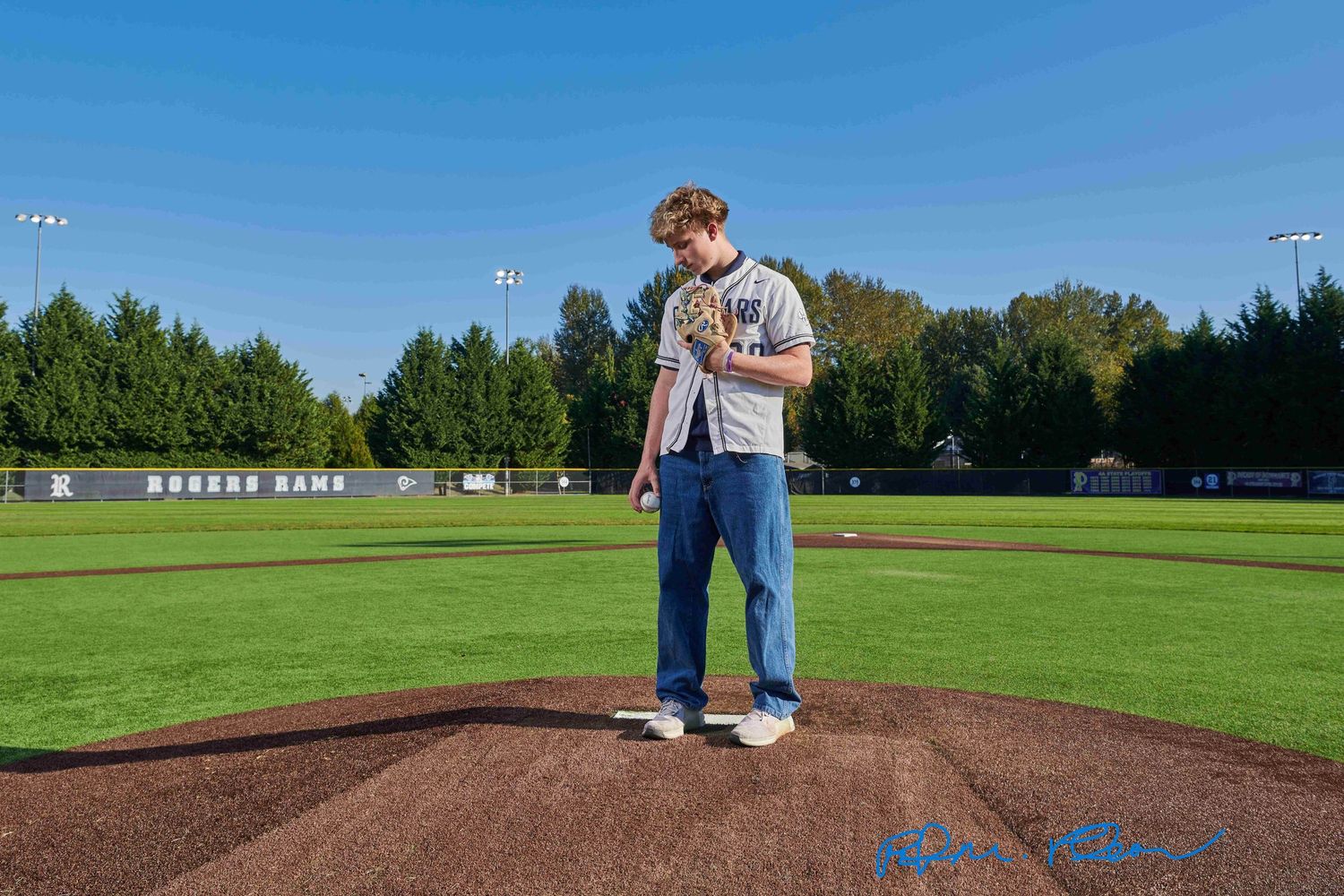 High school senior male at Heritage Recreation Center, Puyallup, standing on pitcher's mound on baseball field.