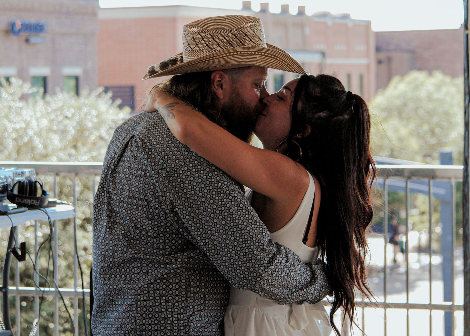 A couple shares a romantic kiss on a balcony in a series of connected photos.