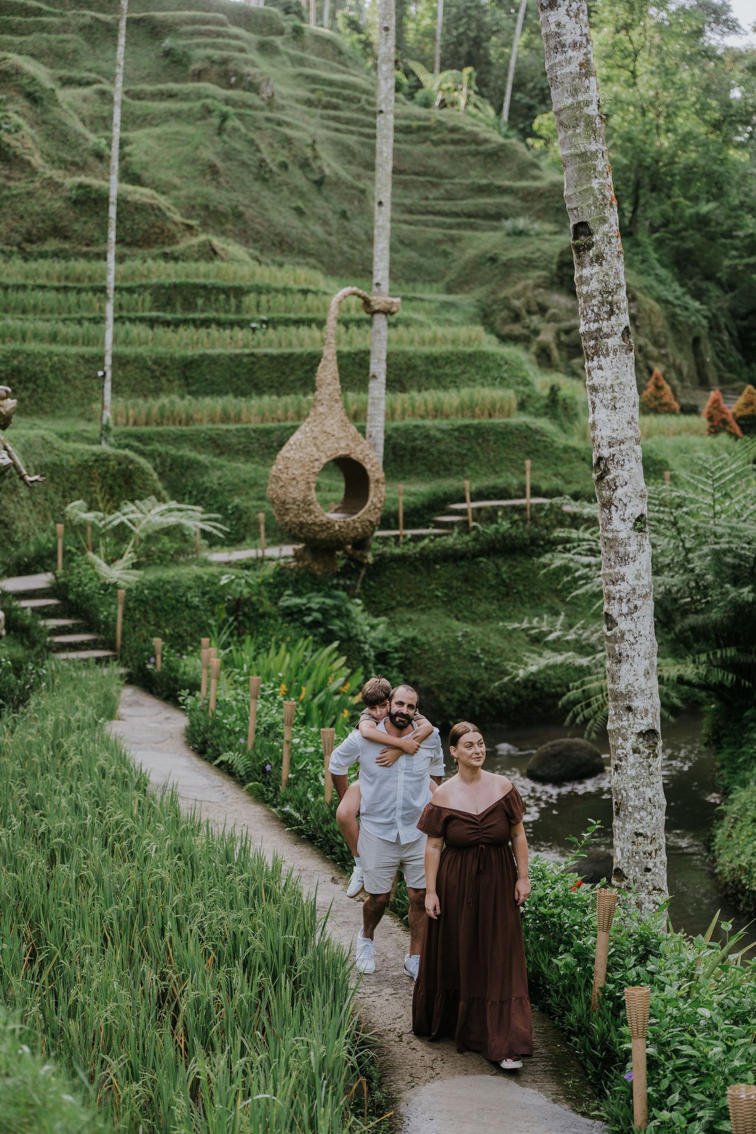 Couple walking along a green garden pathway surrounded by tropical plants.