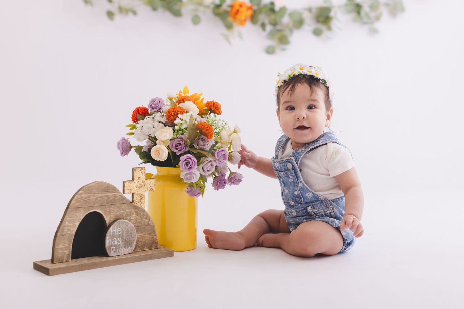 smiling baby easter mini session with he is risen sign