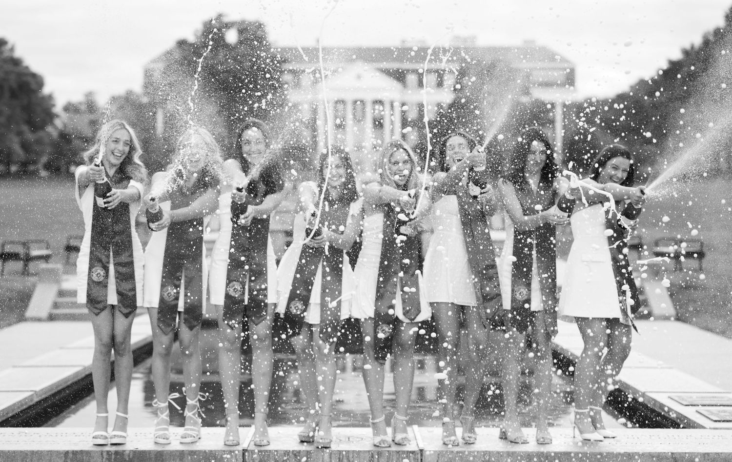 Black and white photo of graduates throwing glitter in celebration.
