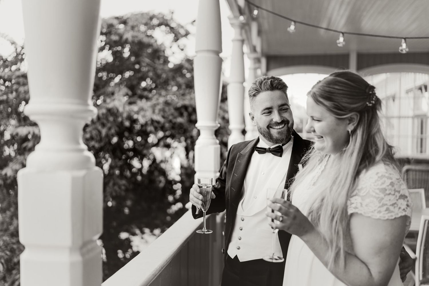 A romantic black and white wedding moment captured on a porch with string lights.