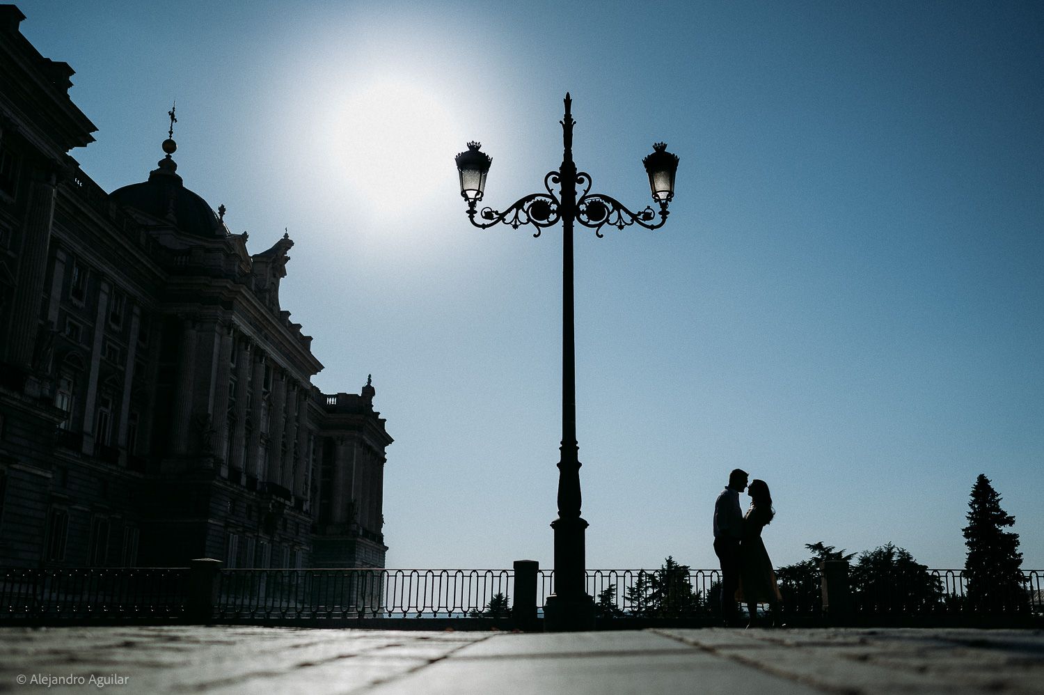 Couple smiling together near ornate church with bell tower under blue sky in Madrid.