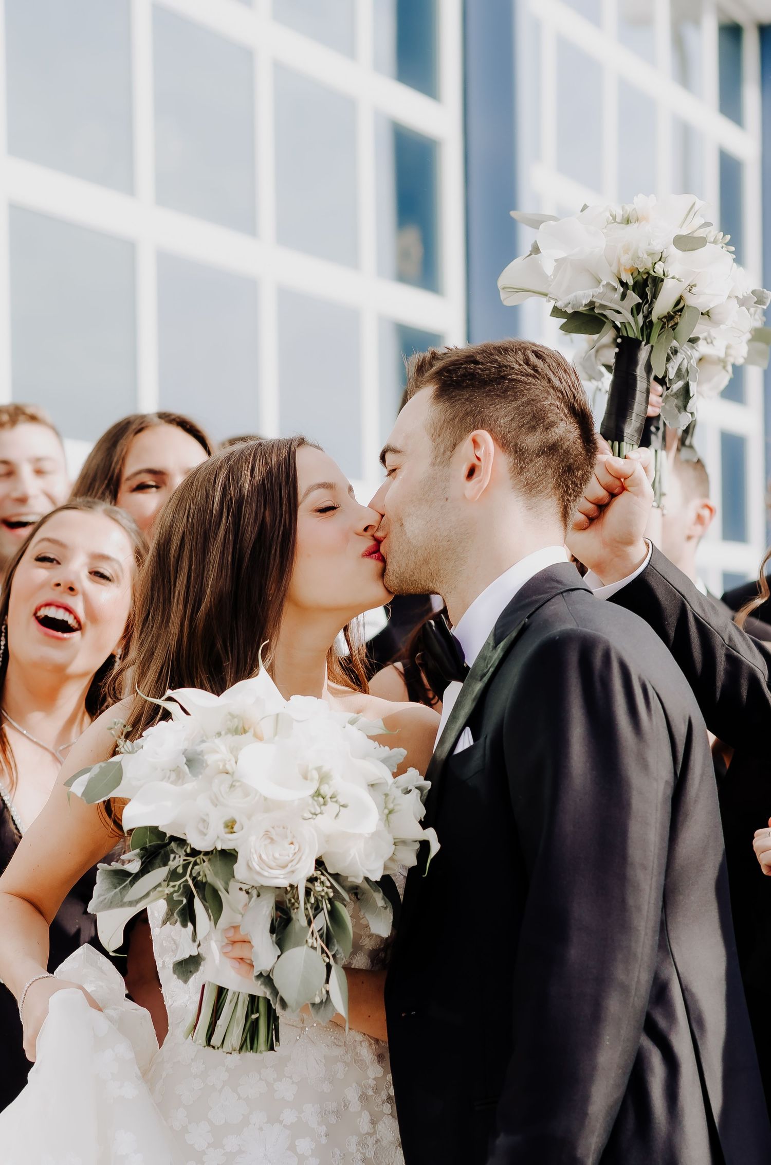 A joyful wedding celebration moment with white bouquets and formal attire.