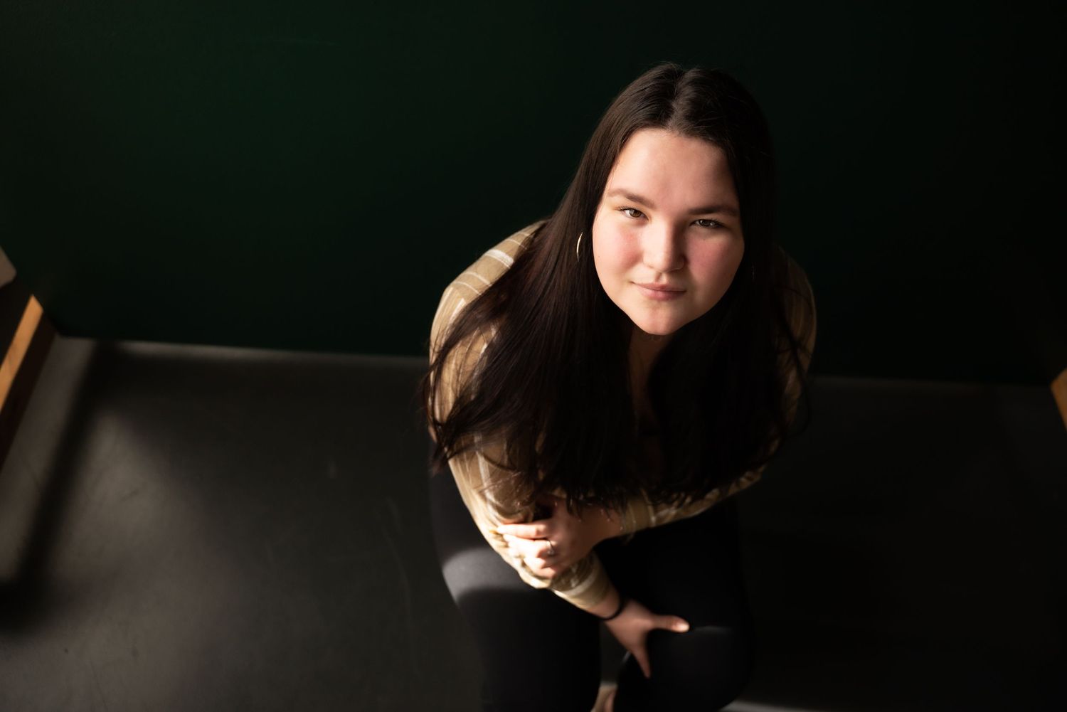senior girl looks up at camera with dramatic lighting in a mount vernon, wa studio