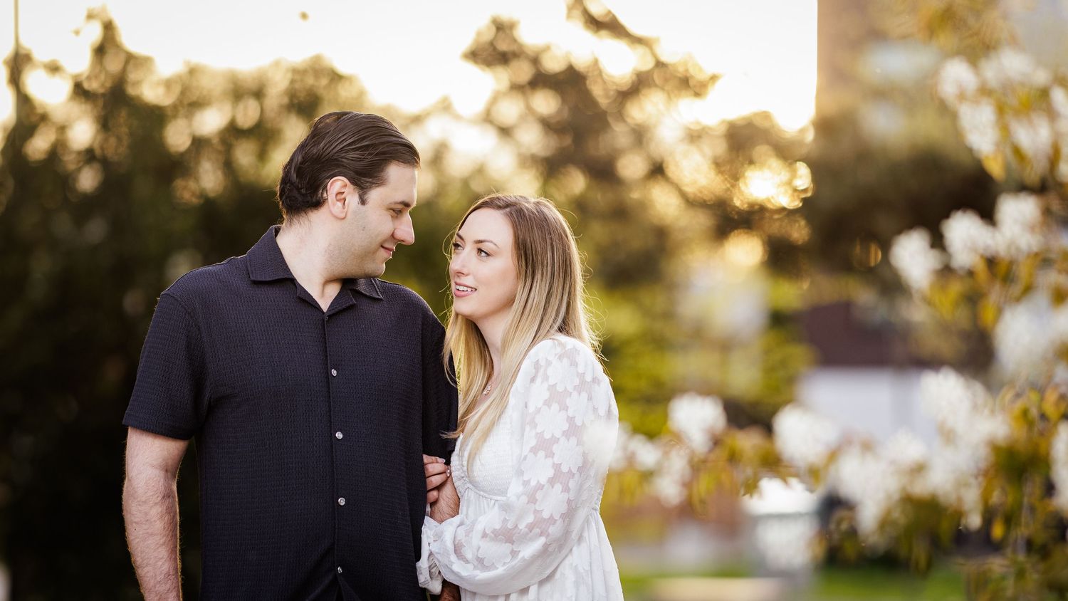 Romantic spring engagement photos captured among blooming cherry blossoms at sunset.
