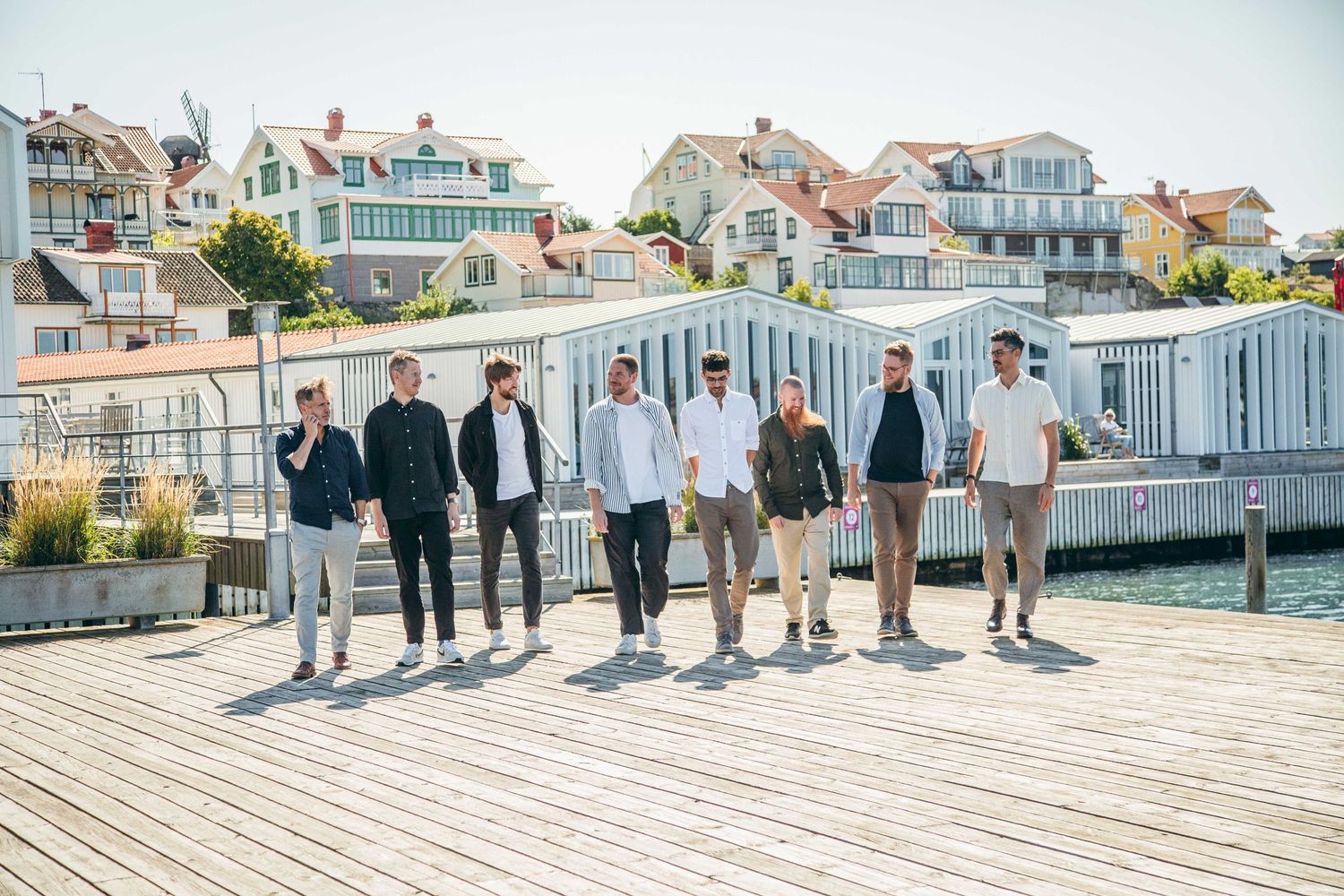 Group photo of people standing on a seaside boardwalk with coastal homes in background.