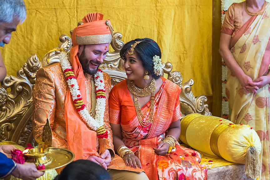 Traditional Indian wedding ceremony showing guests and decorations against a vibrant yellow backdrop.
