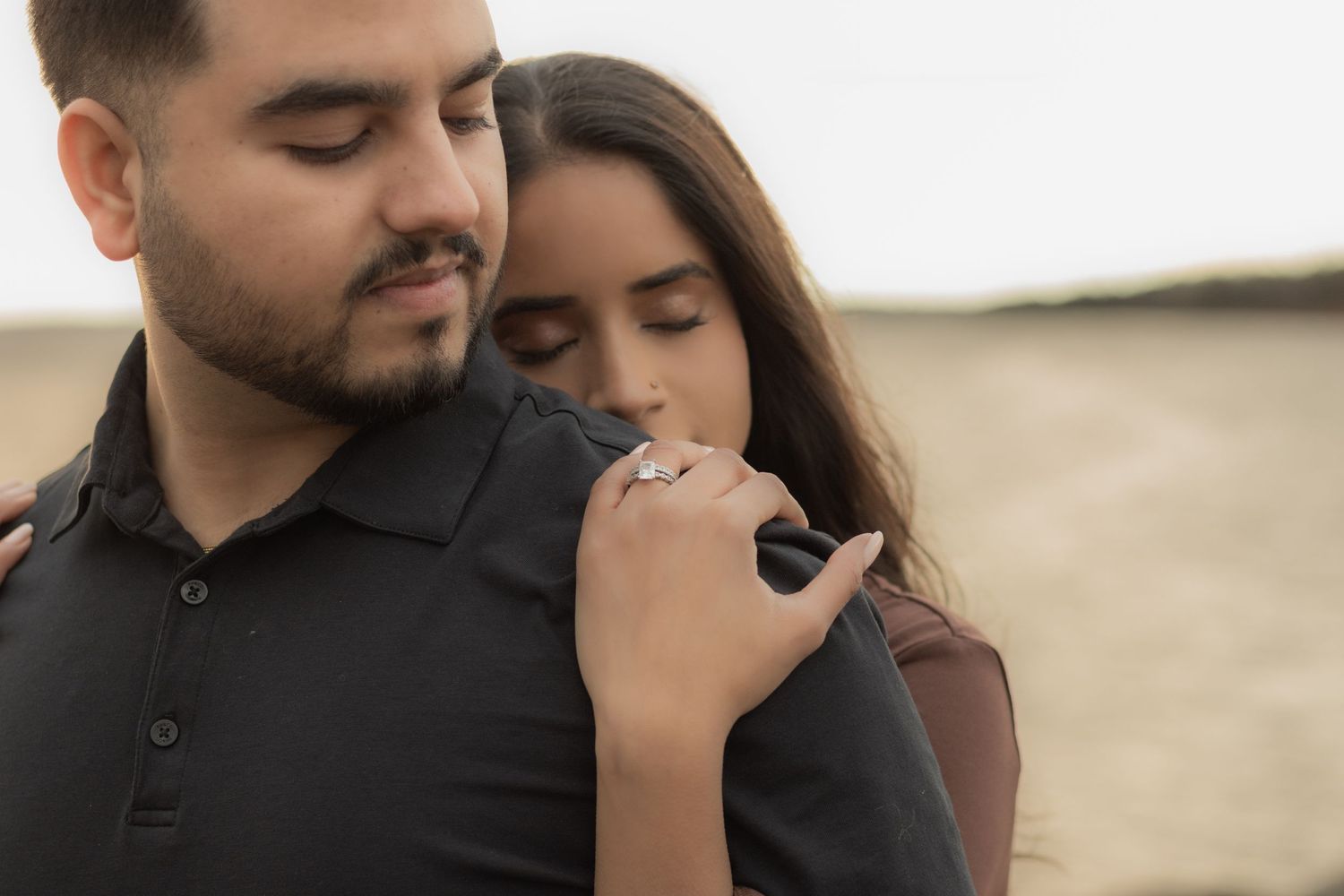 A tender embrace between a couple against a misty neutral background.