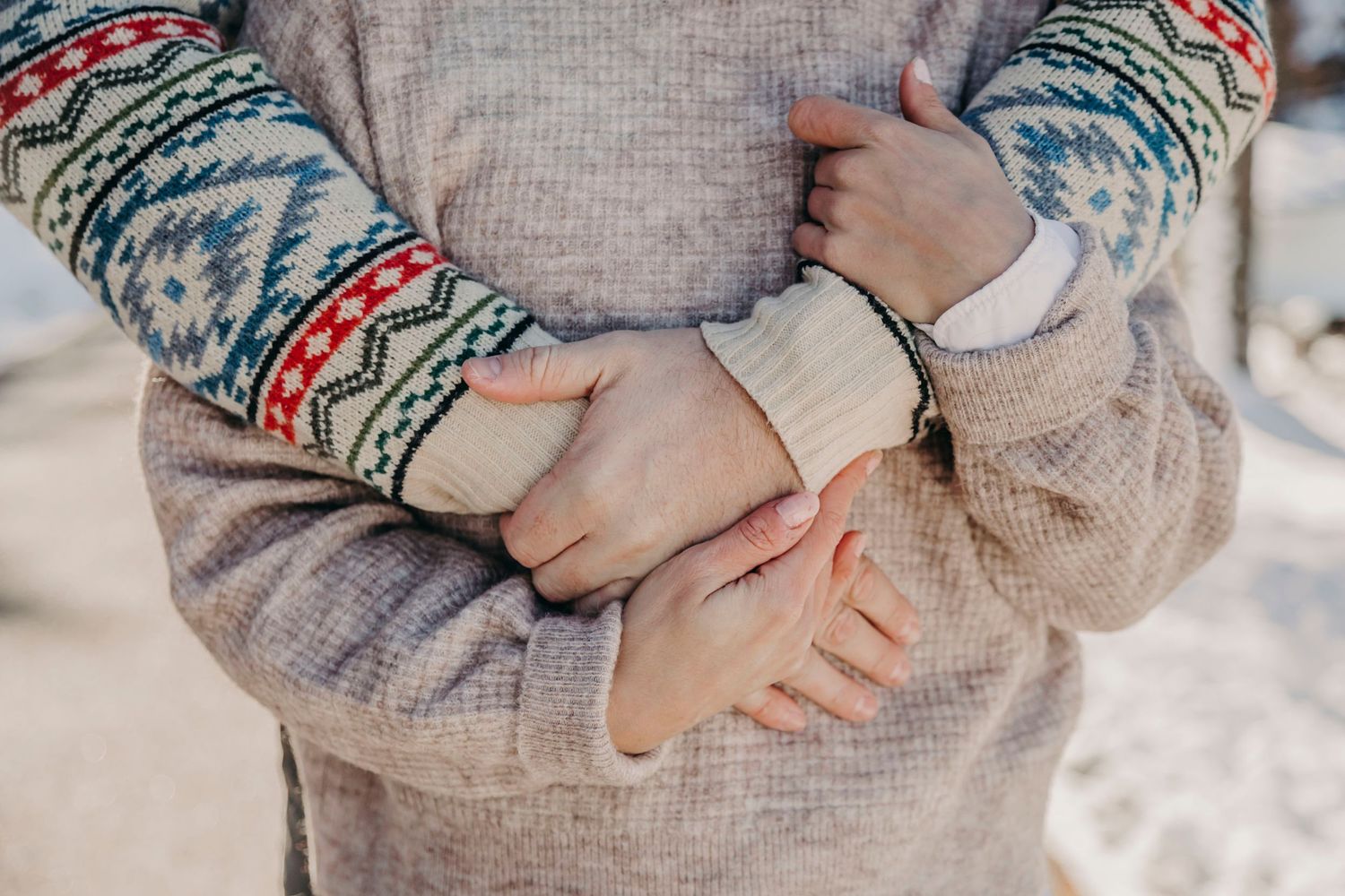 Close up detail of hands wearing a patterned winter sweater with Nordic design.