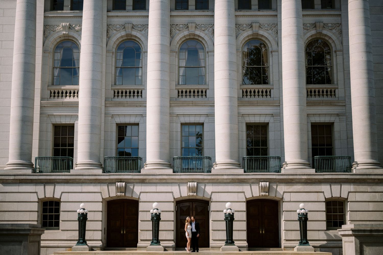 A grand neoclassical building entrance with tall white columns and ornate arched windows stands majestically.