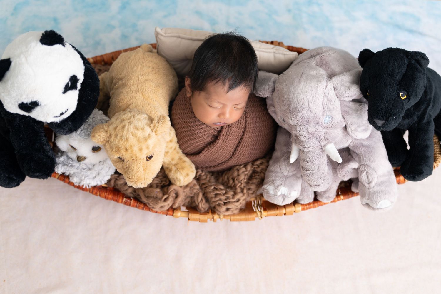 A collection of plush stuffed animals including a panda, dog, elephant, and panther arranged on a white surface.