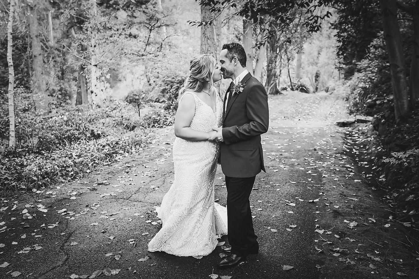 Black and white romantic wedding photos captured in a dreamy forest setting with falling autumn leaves.