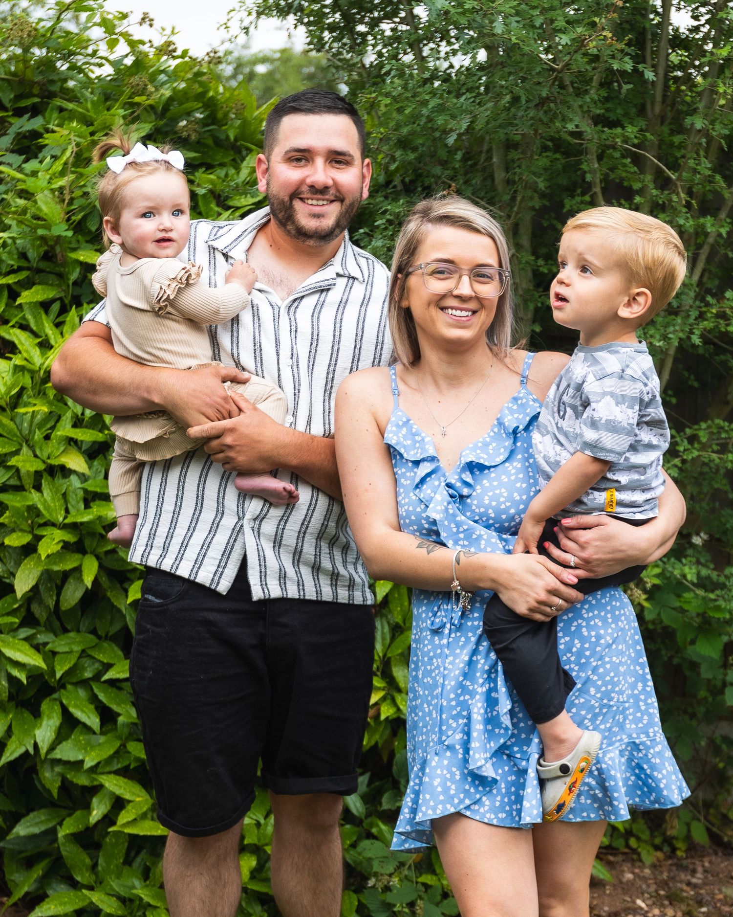 man, woman and two young children, a small happy family having their picture.