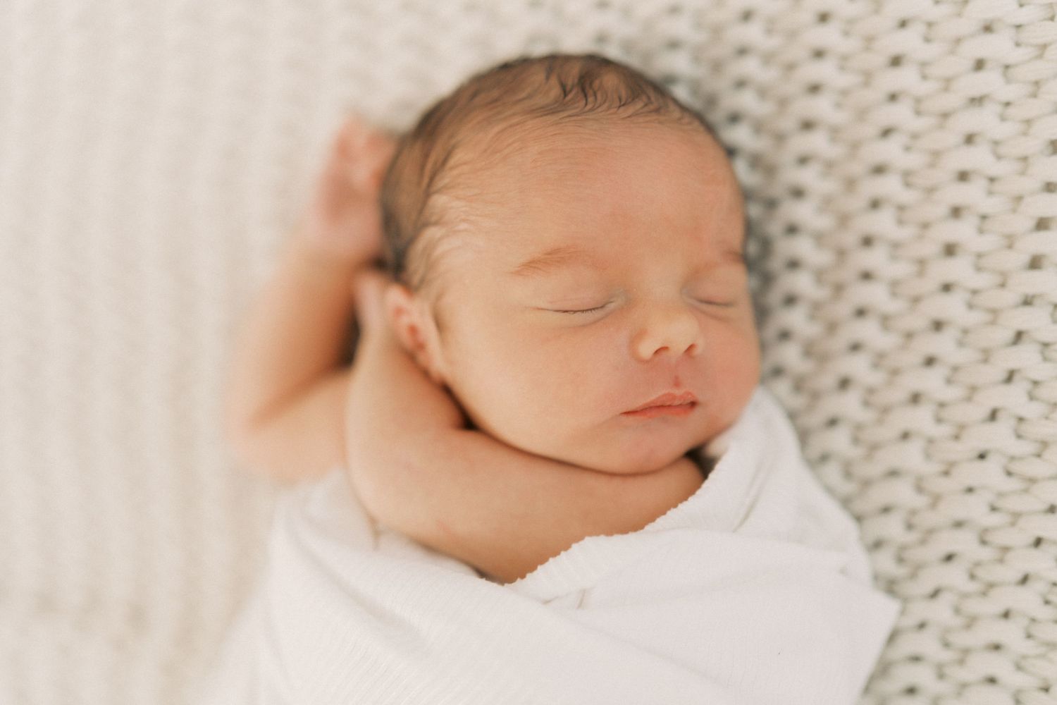 A family spends time together in a light-filled room with a tan carpet and white sofa, sitting near a woven basket.