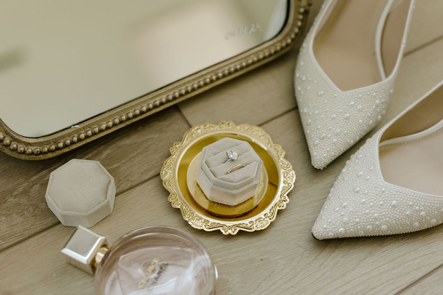Elegant white lace wedding shoes with pearl details and gold accents arranged in a row on wooden surface.
