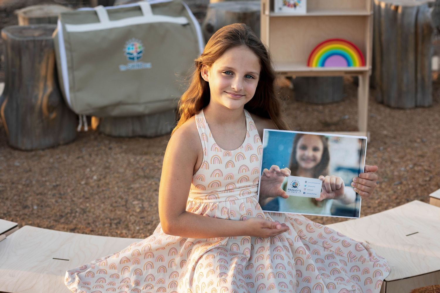 A Young Girl holds up her own companies AD proudly.