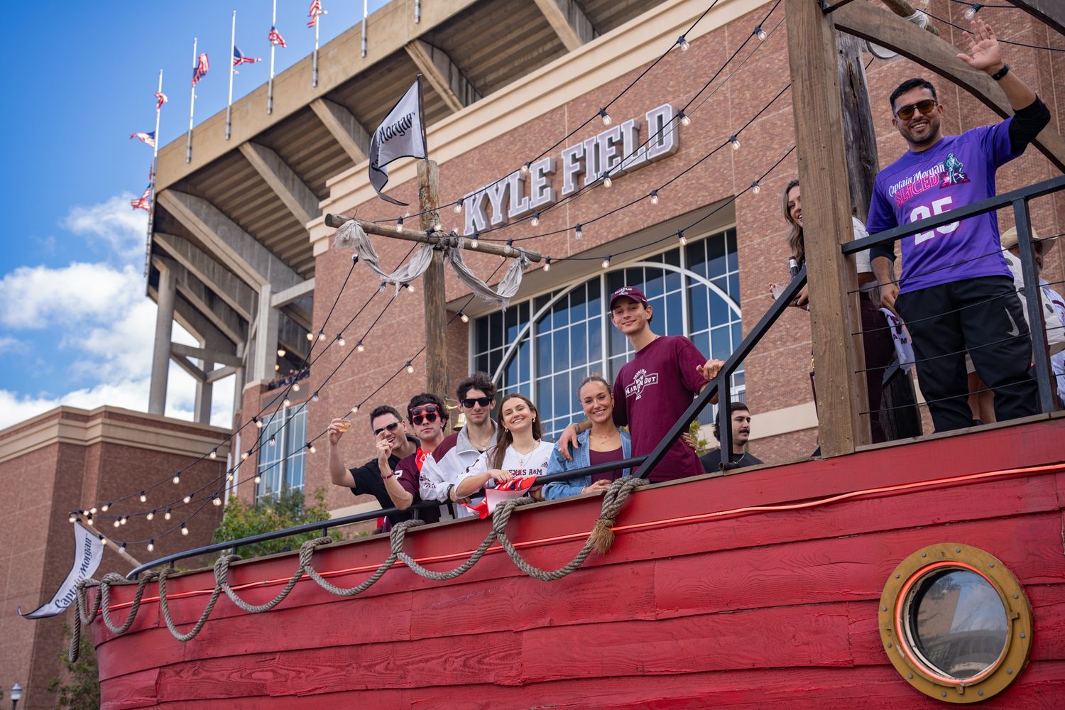 Students gather on red-painted steps outside a brick university building during a campus event.