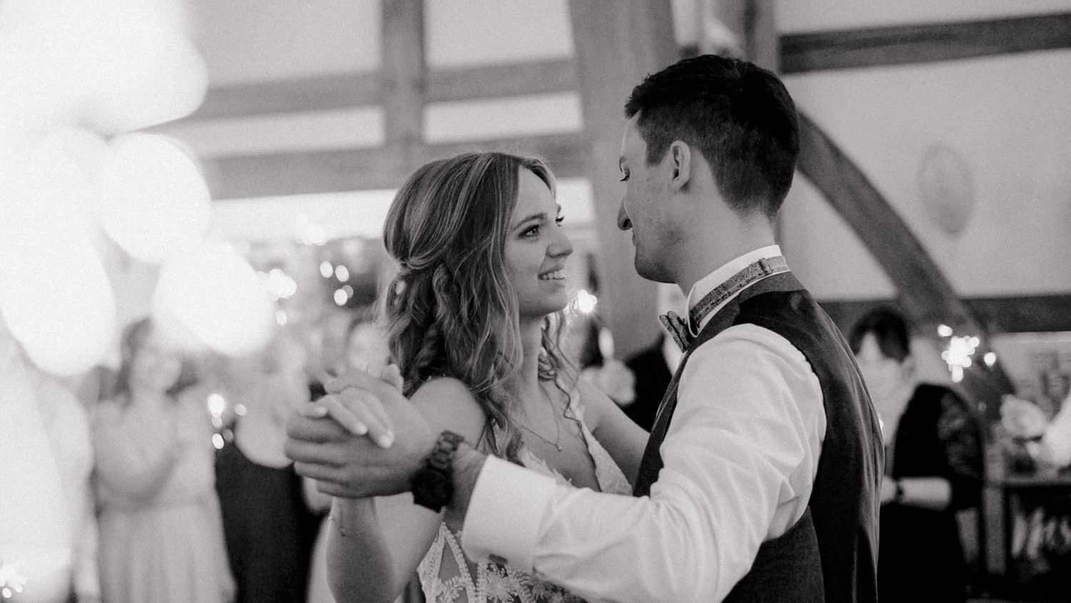 A couple shares a romantic dance at their wedding reception while other couples dance in the background.