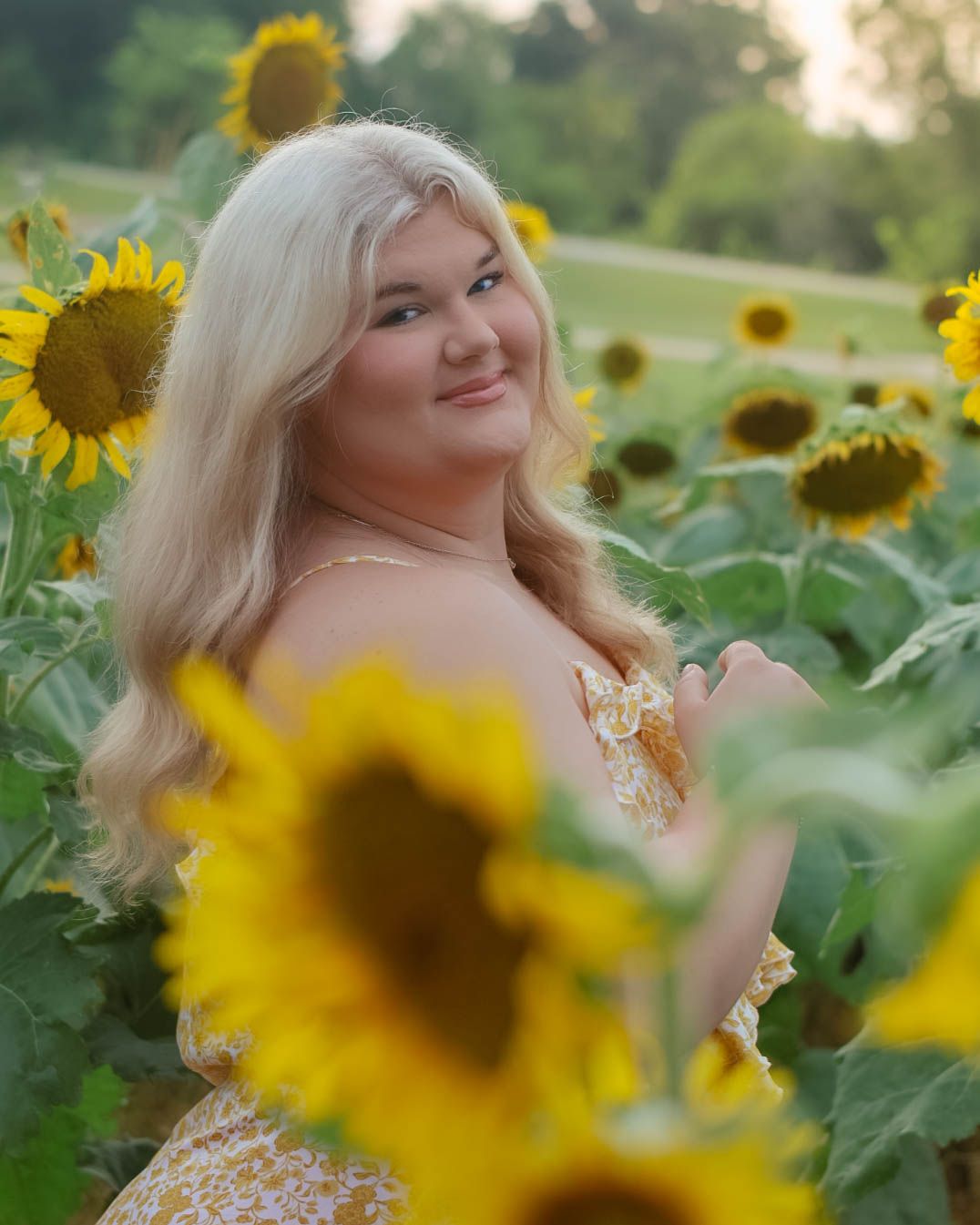 Portrait in vibrant sunflower field during golden hour.