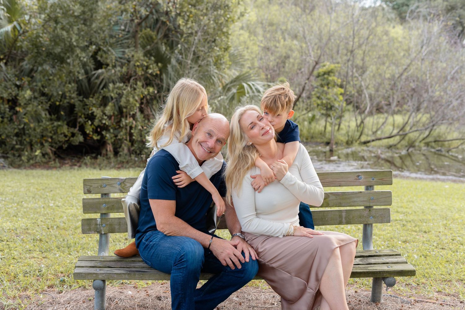 Romantic engagement photo session in a rustic outdoor setting with wooden benches and natural greenery.