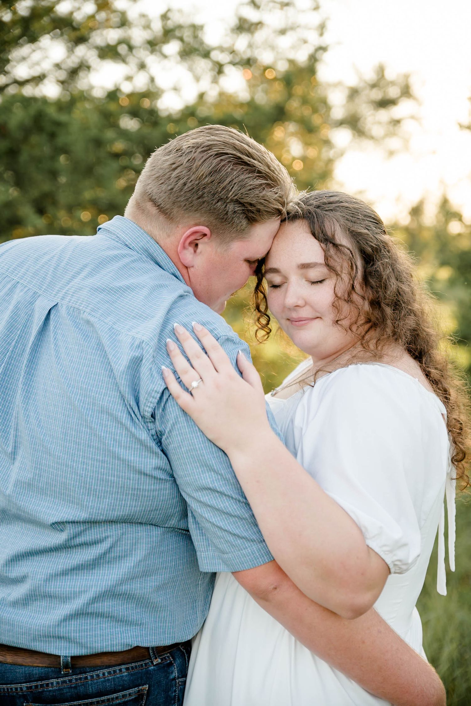 A happy couple at their wedding celebration with a beautiful floral bouquet featuring white and blue flowers in a rustic setting.