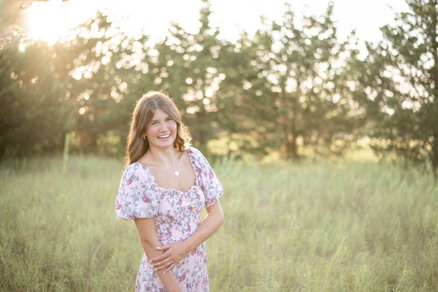 A couple poses together at sunset in an outdoor setting holding a colorful floral bouquet.