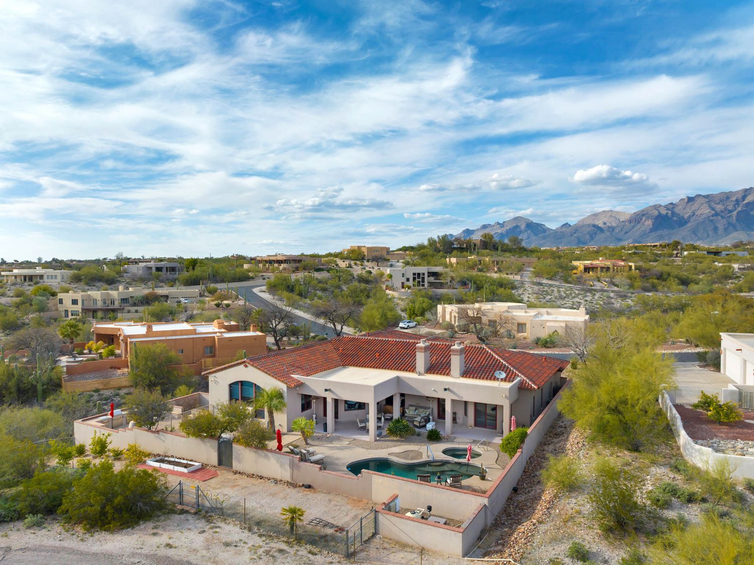Aerial panoramic view of desert homes and mountains in Tucson Arizona with blue skies and scattered clouds.