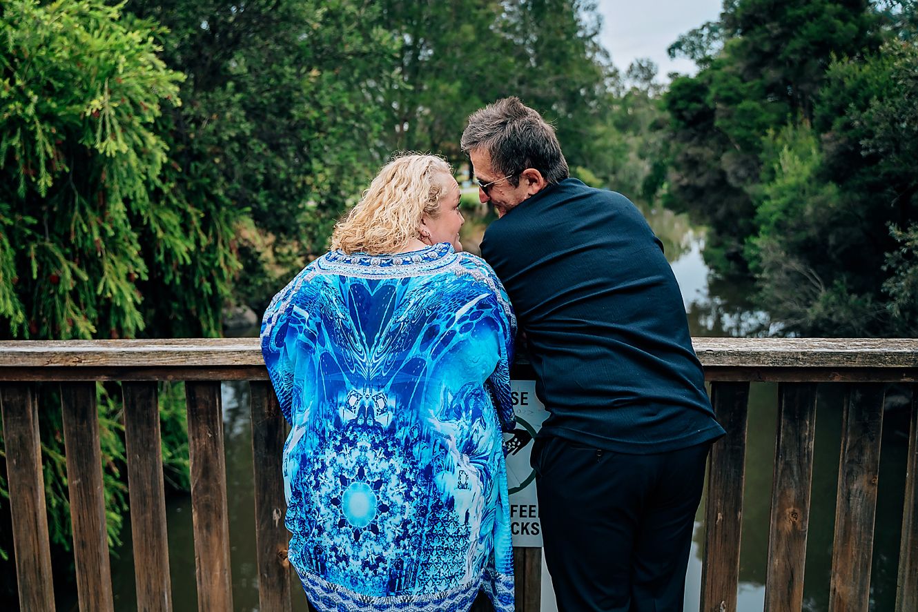 A couple walking on a wooden deck while wearing coordinated blue tie-dye and black outfits.