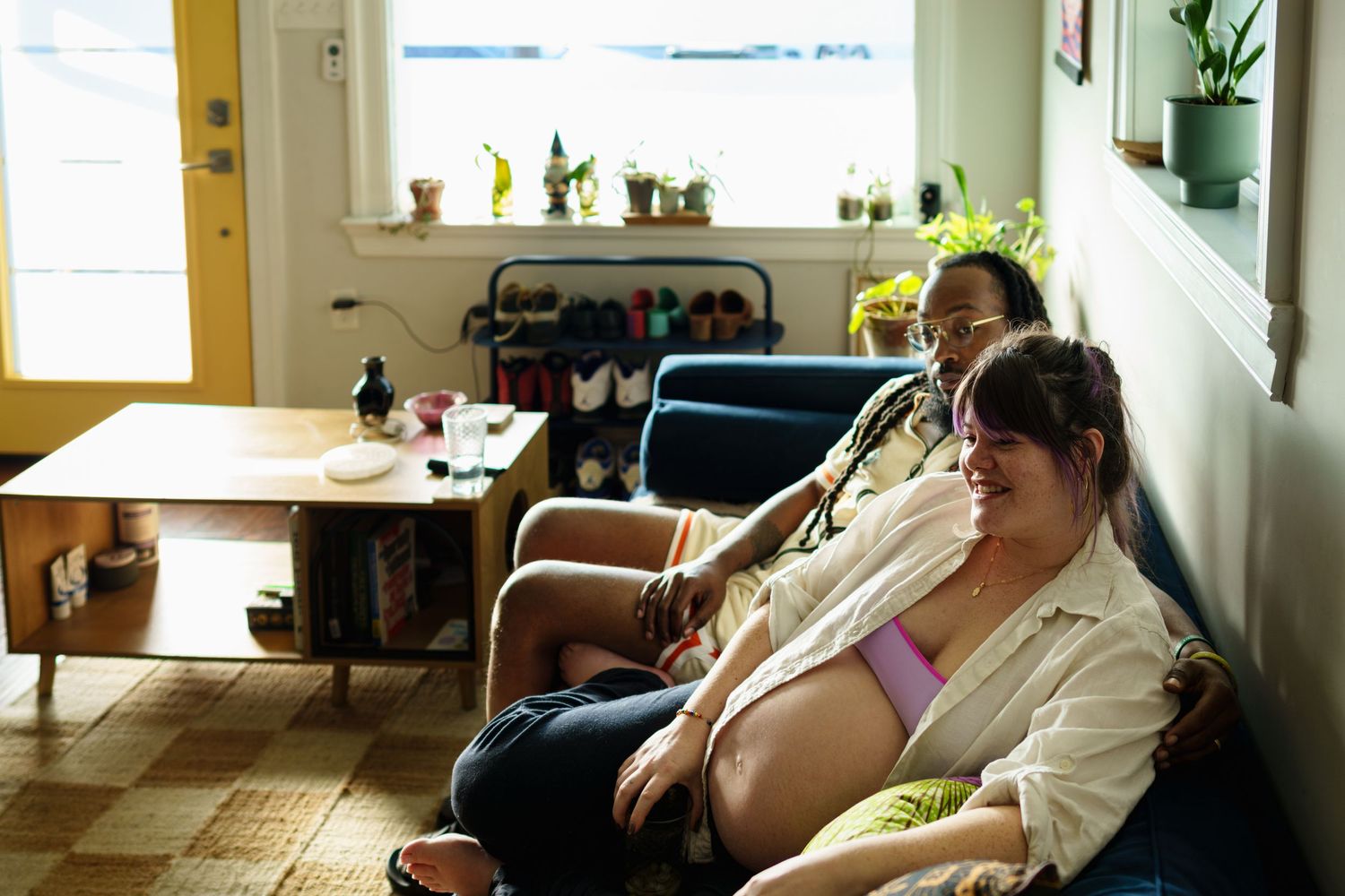 A pregnant mother and her husband sitting on a couch in their New Orleans home during a birth photography consultation.