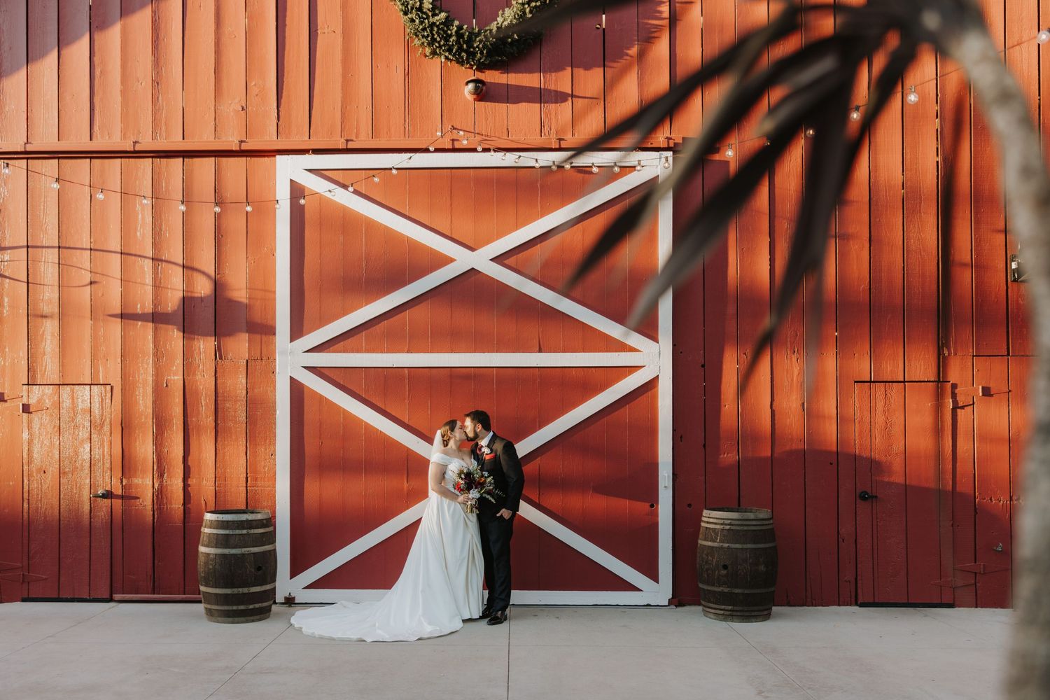 A tender moment between newlyweds posing against a white wall.