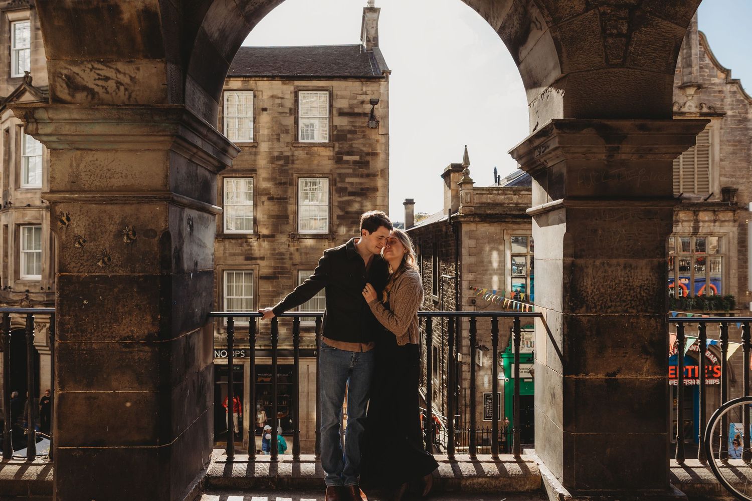 Couple sharing a romantic moment under a stone arch in Edinburgh's historic Old Town.