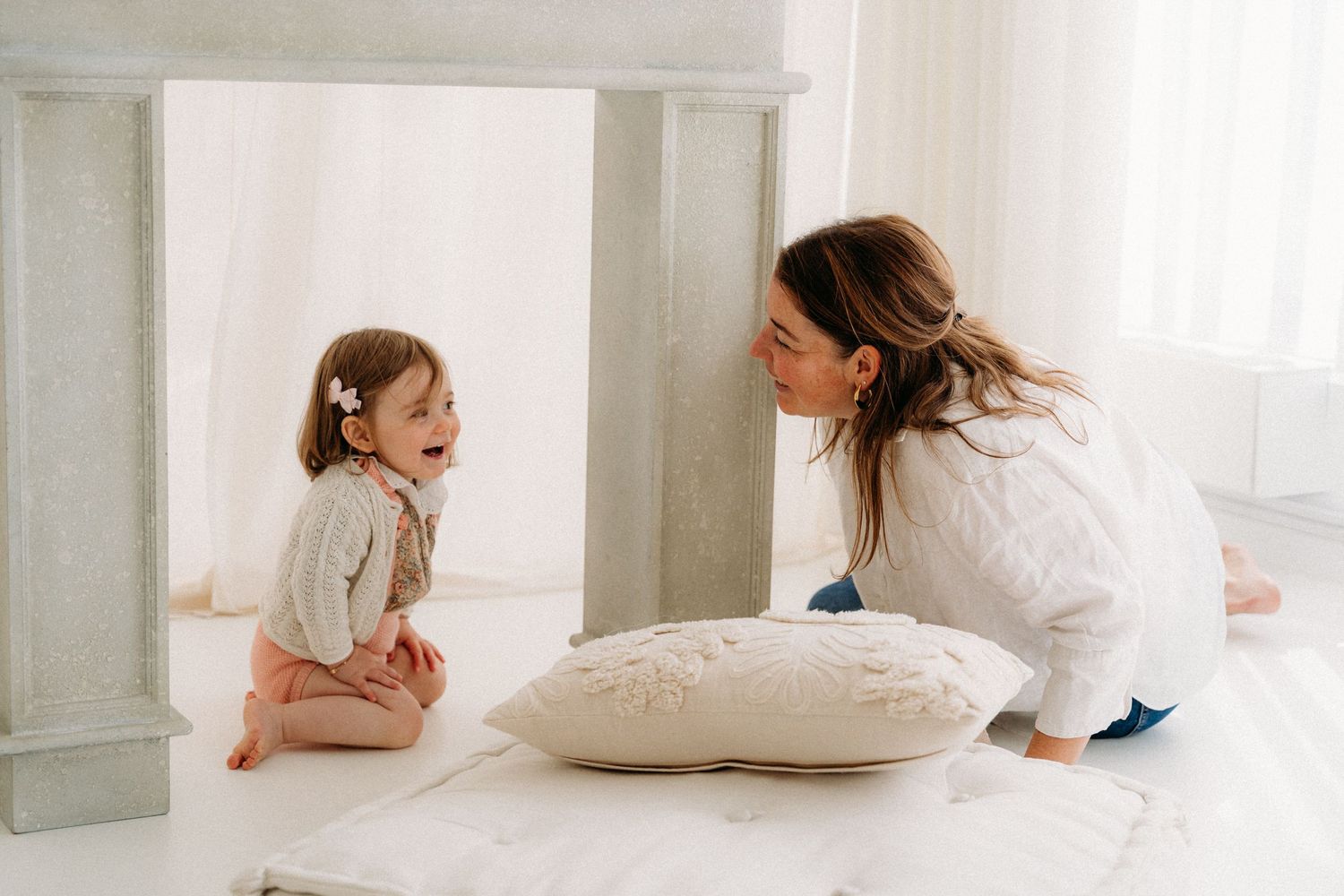 Klein meisje lacht terwijl ze met haar mama speelt tijdens een fotoshoot.