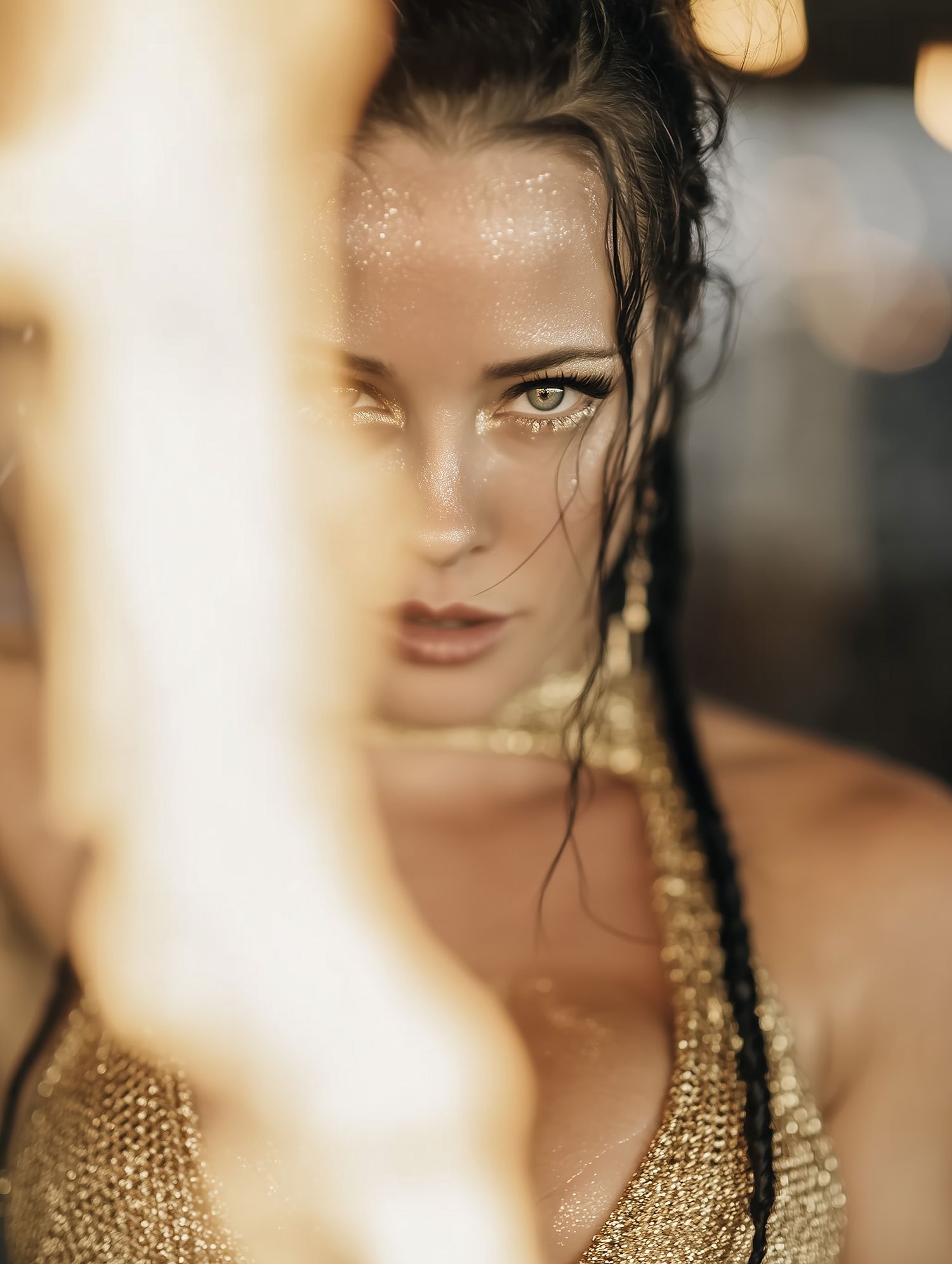 Artistic portrait with selective focus and bokeh lighting effects highlighting golden tones and elegant styling.