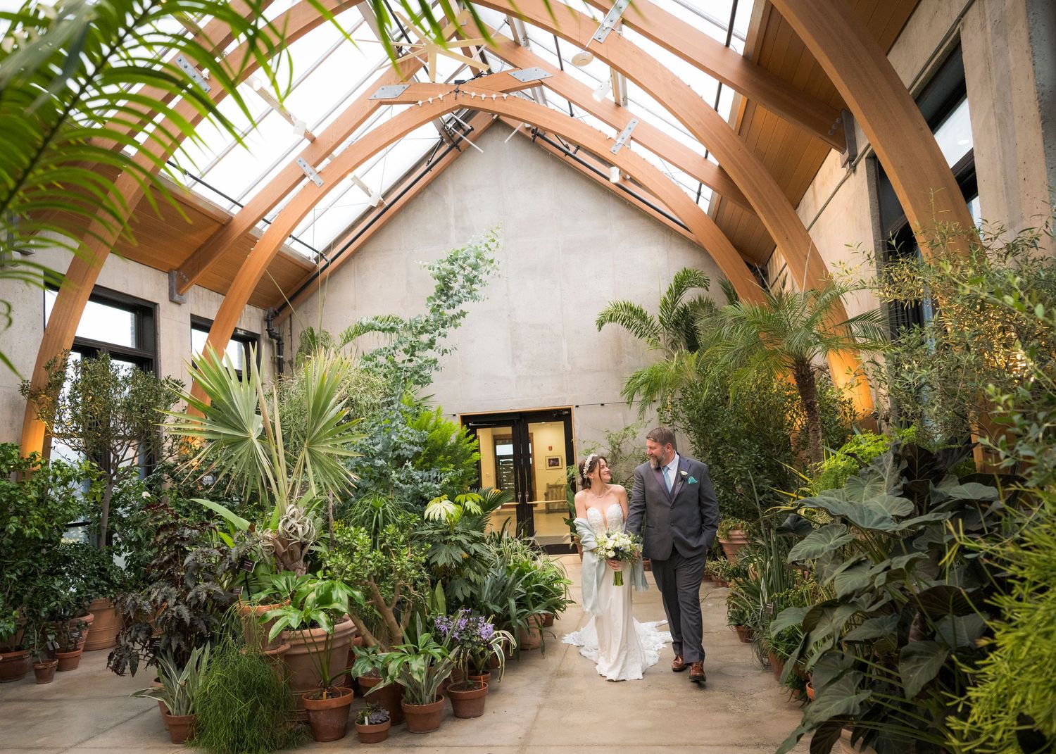 Romantic wedding couple poses in a spring garden with hanging white decorative spheres.