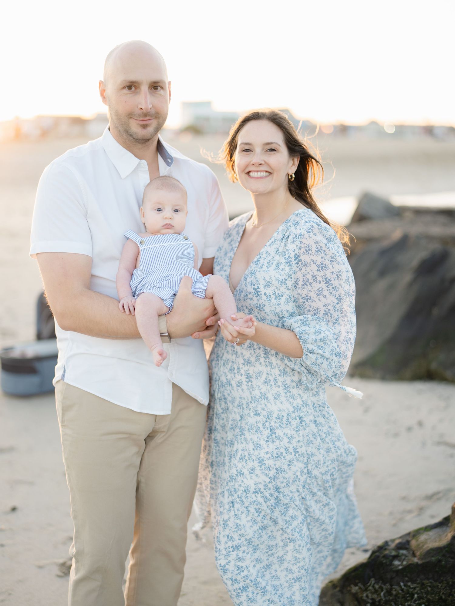 Belmar NJ newborn photographer capturing parents holding baby at golden hour on Belmar Beach.