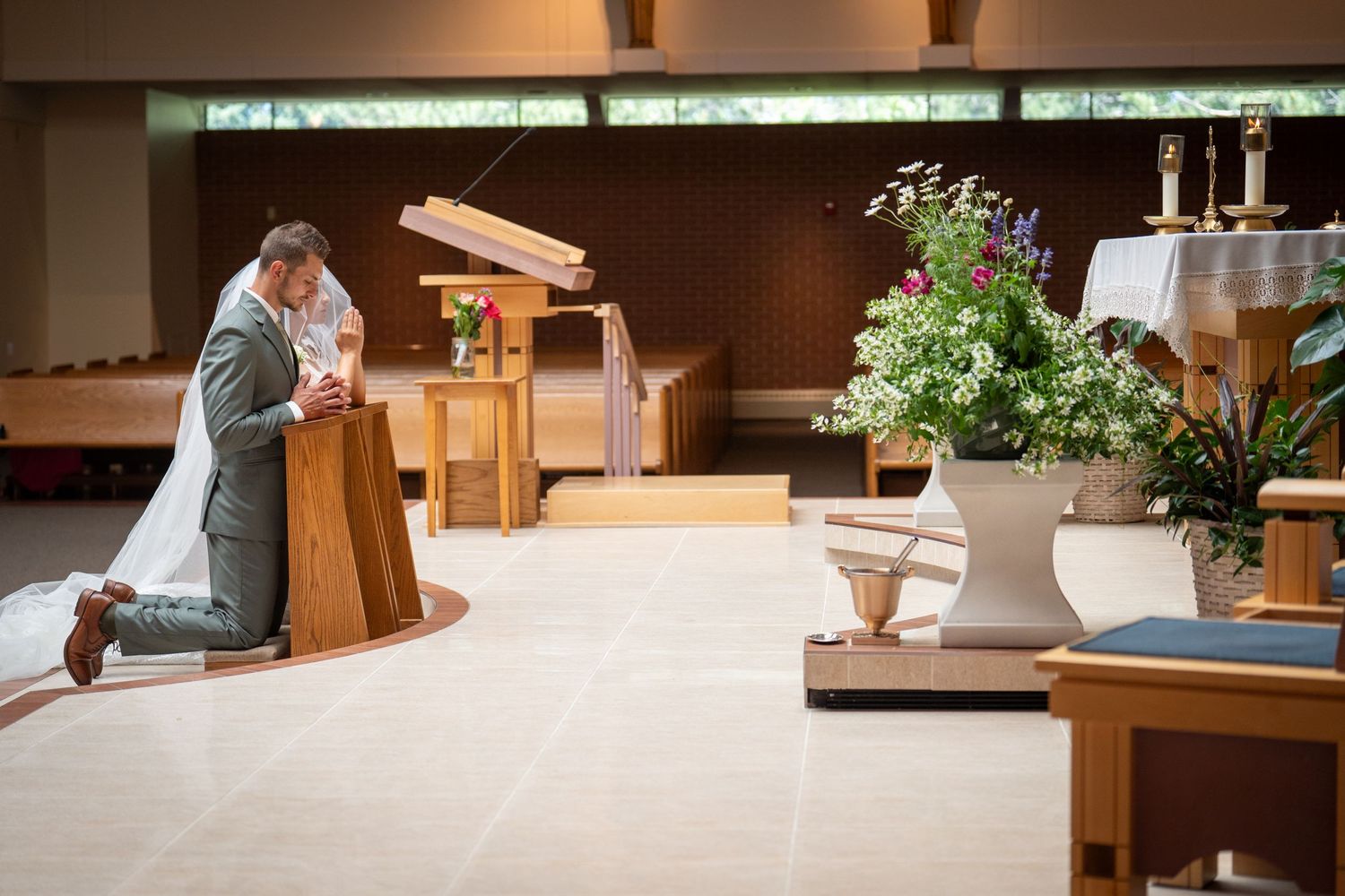 A couple prays together at a church altar during their wedding ceremony.