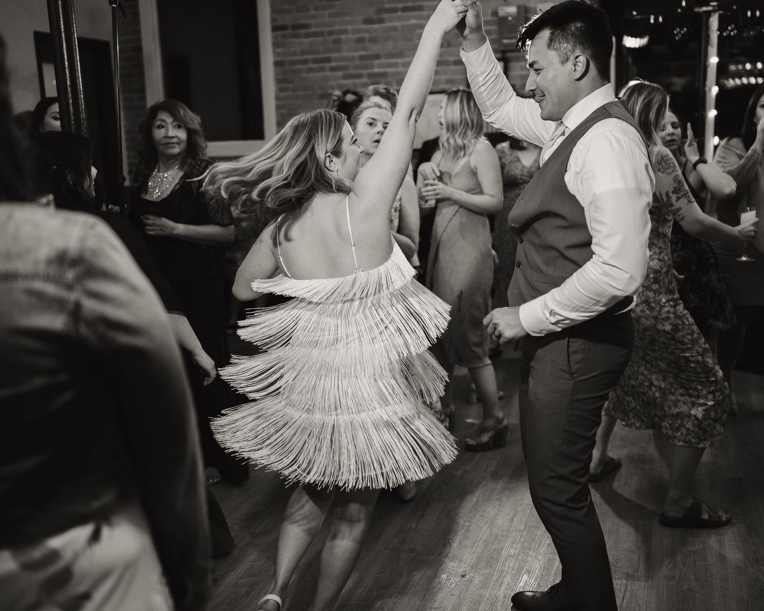 Dancers in vintage attire swing dancing at a lively party venue.