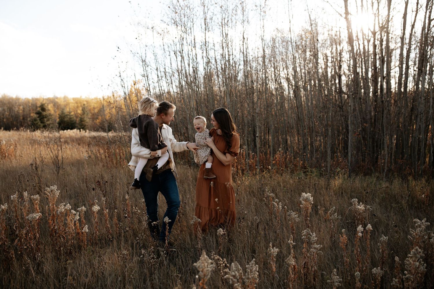 A romantic couple poses together in a scenic field during golden hour.