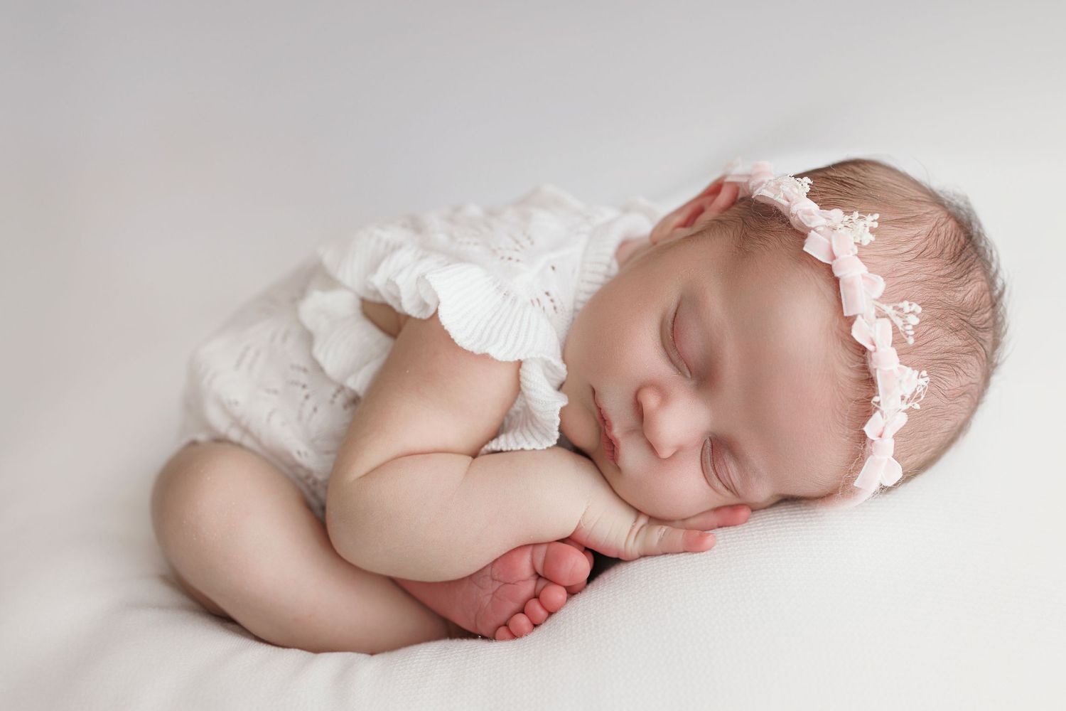 A series of peaceful newborn baby photographs in soft white tones showing gentle sleeping poses on a light backdrop.