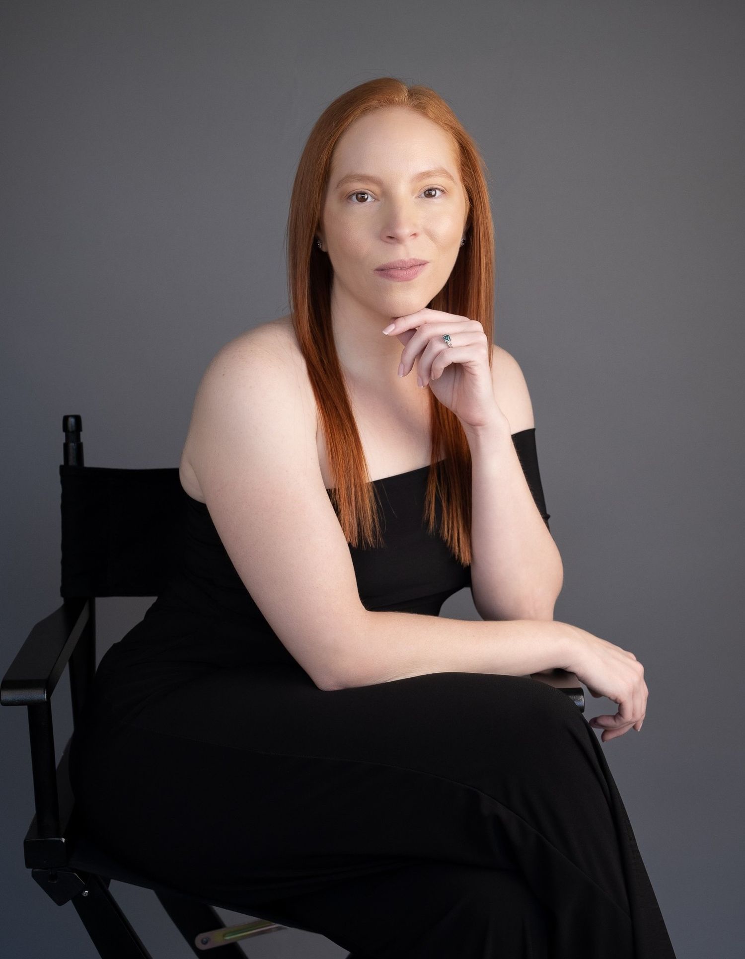 Artistic portrait series in black dress against grey backdrop with moody lighting.