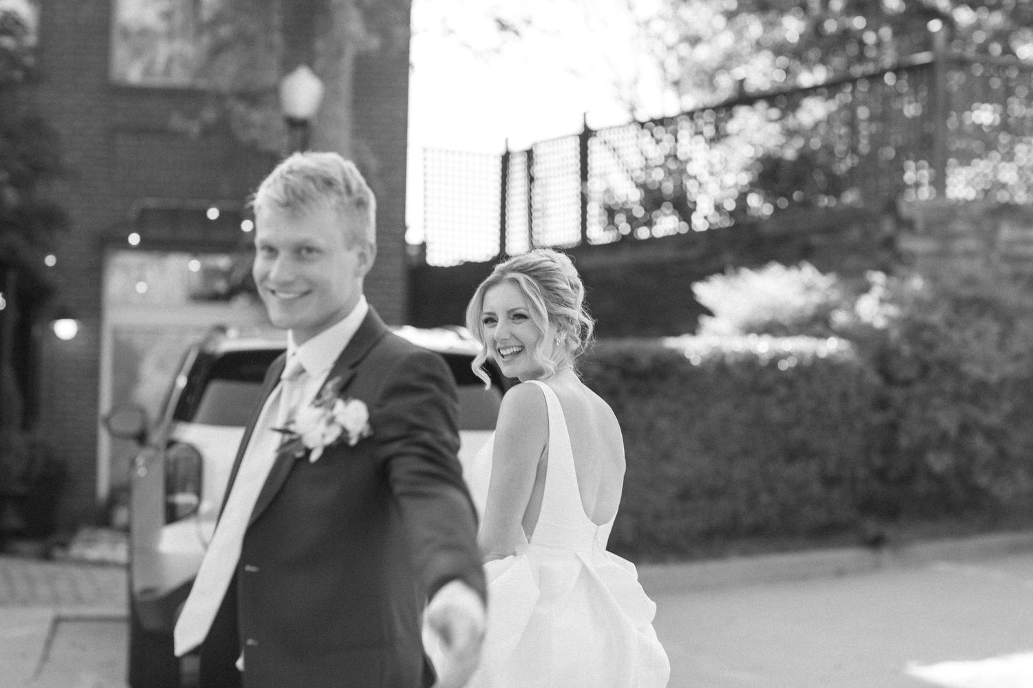 A bride and groom share a joyful moment together during their wedding celebration in black and white photography.